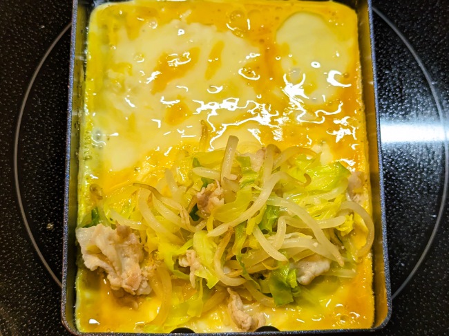 半熟卵の上にとん平焼きの具材をのせる