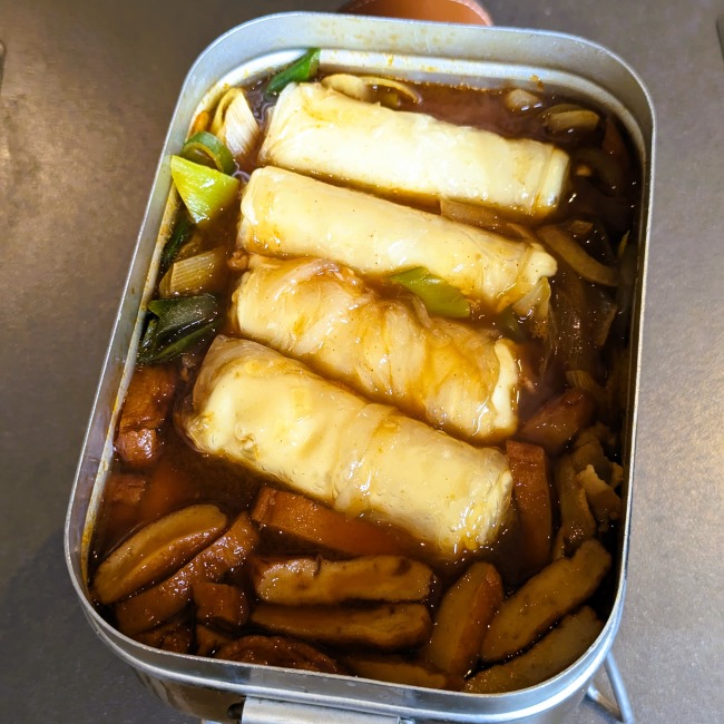 メスティンに煮えた野菜の中にライスペーパートッポギを入れる