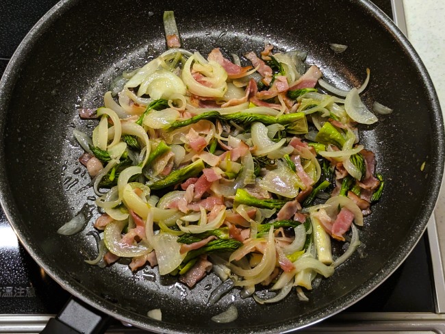 タラの芽とベーコンのバターパスタの野菜を炒める