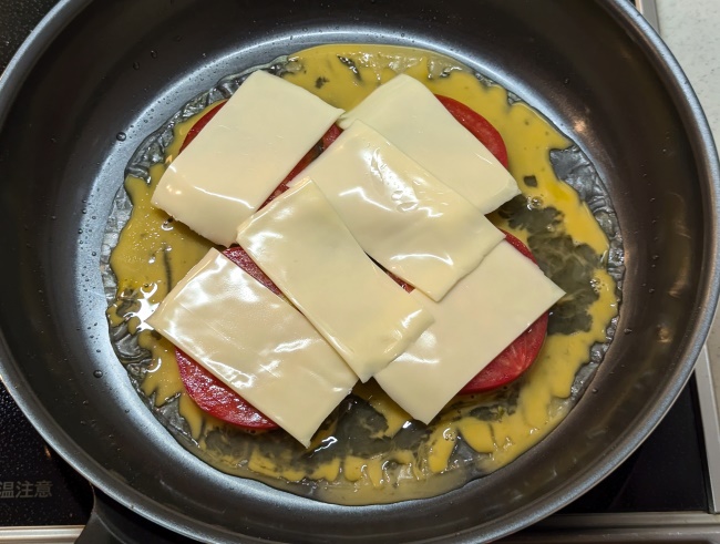 ライスペーパーの上に溶き卵とスライストマトとスライスチーズをのせる