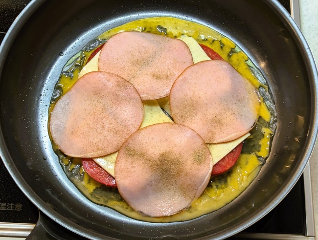 ライスペーパーの上に溶き卵とスライストマトとスライスチーズとハムをのせる