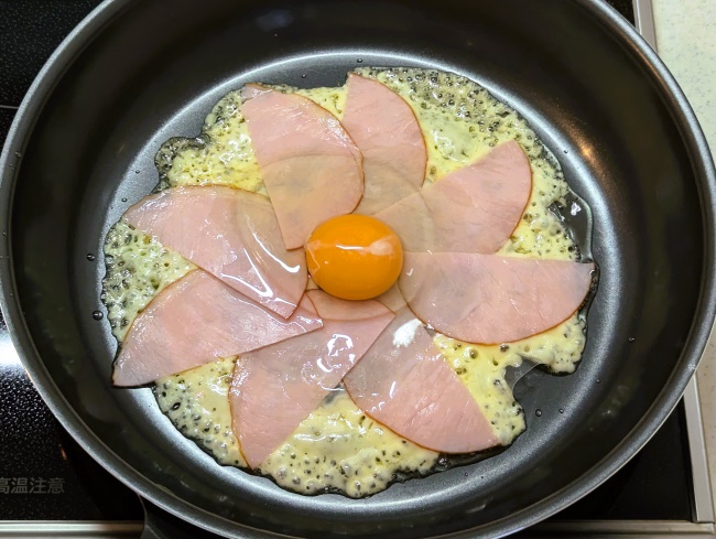 ライスペーパー上のとろけるチーズにハムと卵をのせる