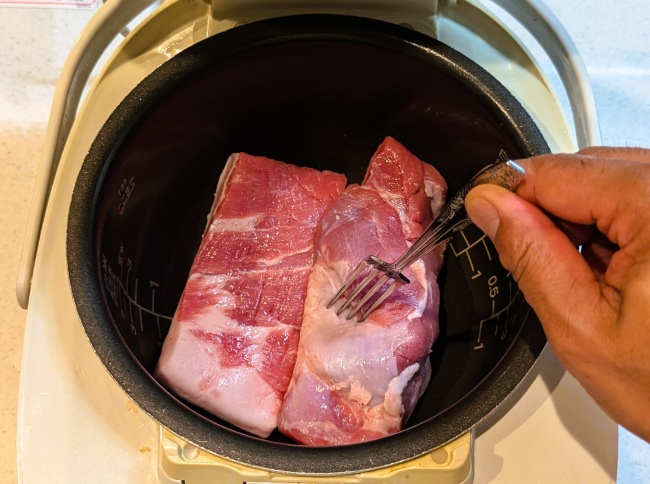 豚肉をフォークで刺し味をしみ込ませる