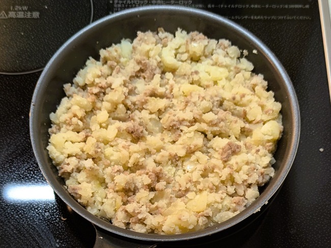 ひき肉と玉ねぎを炒めた具にじゃがいもを入れて混ぜる