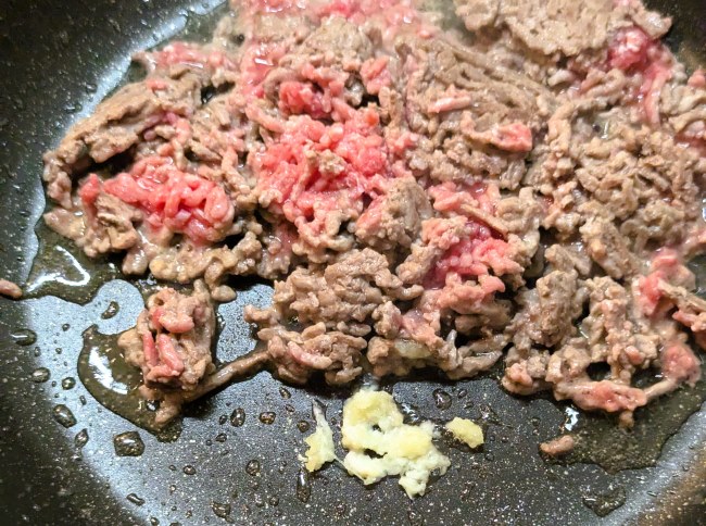 タコライスのミンチににんにくを入れて炒める